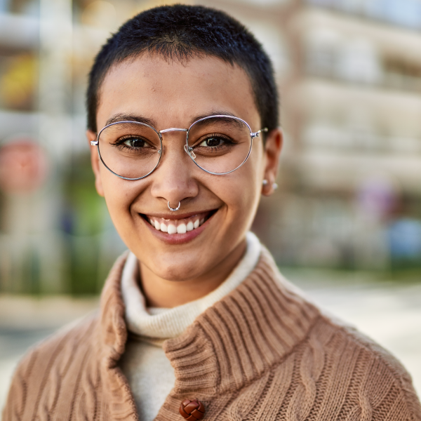 A happy young person wearing glasses and a sweater