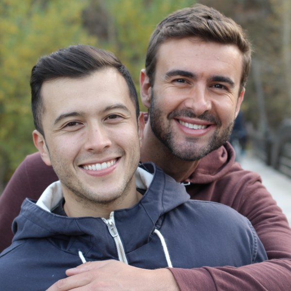 Two men smiling and hugging in the park