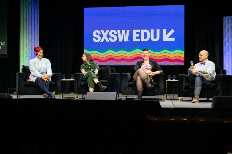 Four people are seated on black chairs on a stage. An image reading SXSW EDU with a rainbow wave drawing beneath the letters appears behind them.